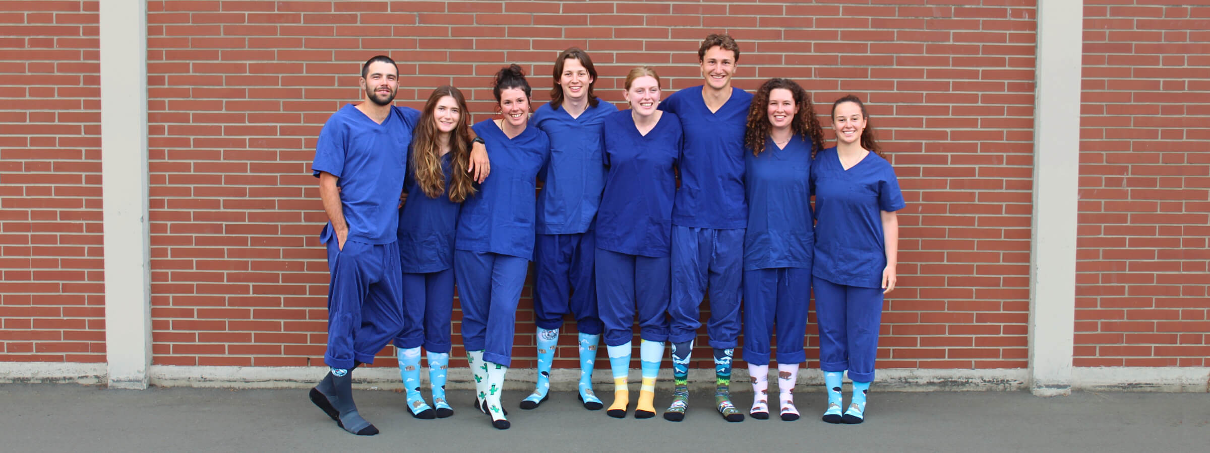 Group of 8 nurses huddled together wearing Scrubcare Footwear's compression socks for nurses.