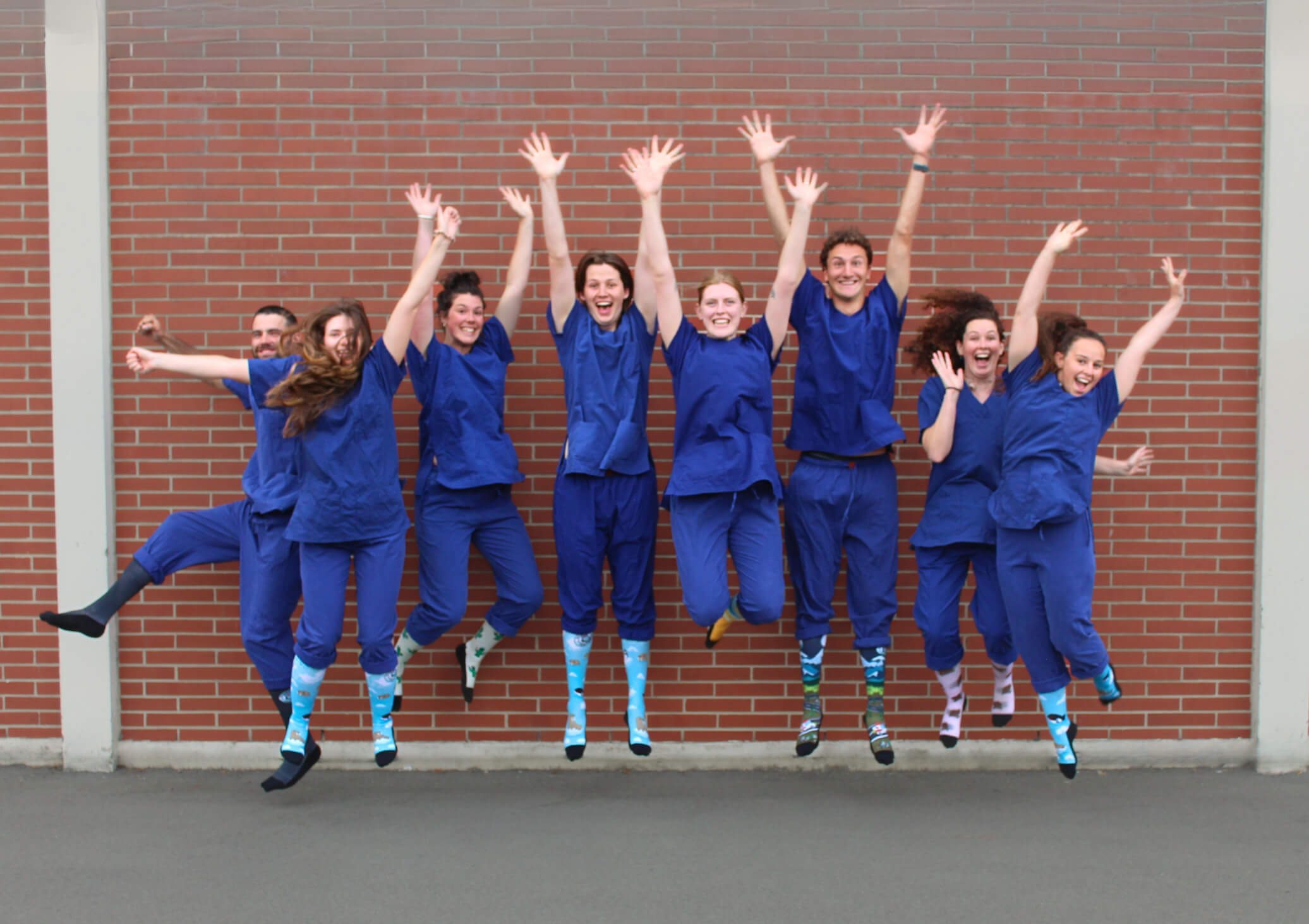 Group of 8 nurses jumping while wearing Scrubcare Footwear's nursing socks.