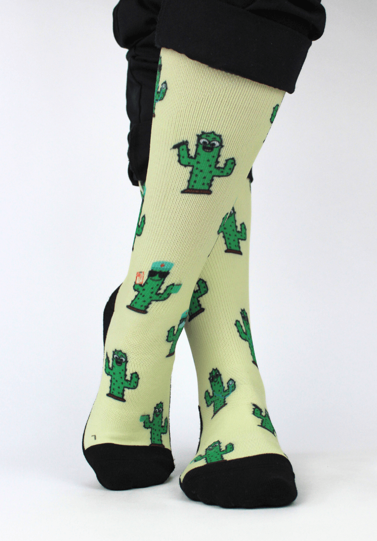 Compression socks for nurses with a cactus design, front view with legs crossed showing 20-30mmHg compression.